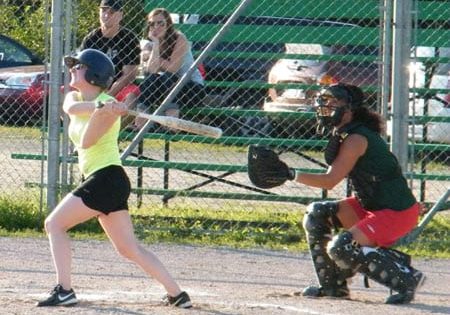 Nelson Missfits' batter Jessica Nowlan sends a shot into the infield, as Nelson Lady Vics catcher Chi Metallic looks on.